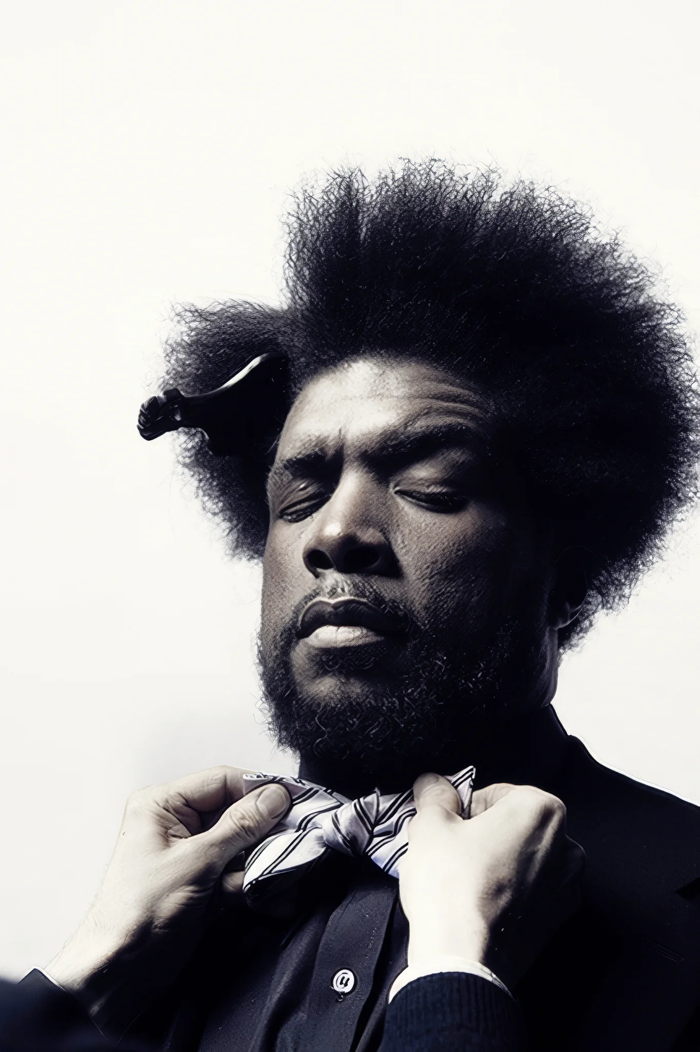 Toned monochrome portrait of a man with an afro having his patterned bow tie adjusted.